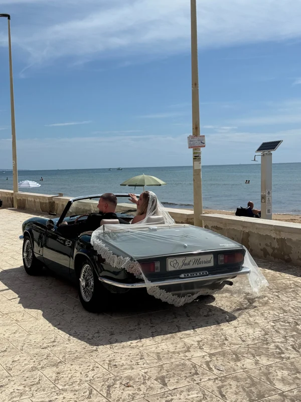 Gli sposi a bordo della Triumph davanti al mare