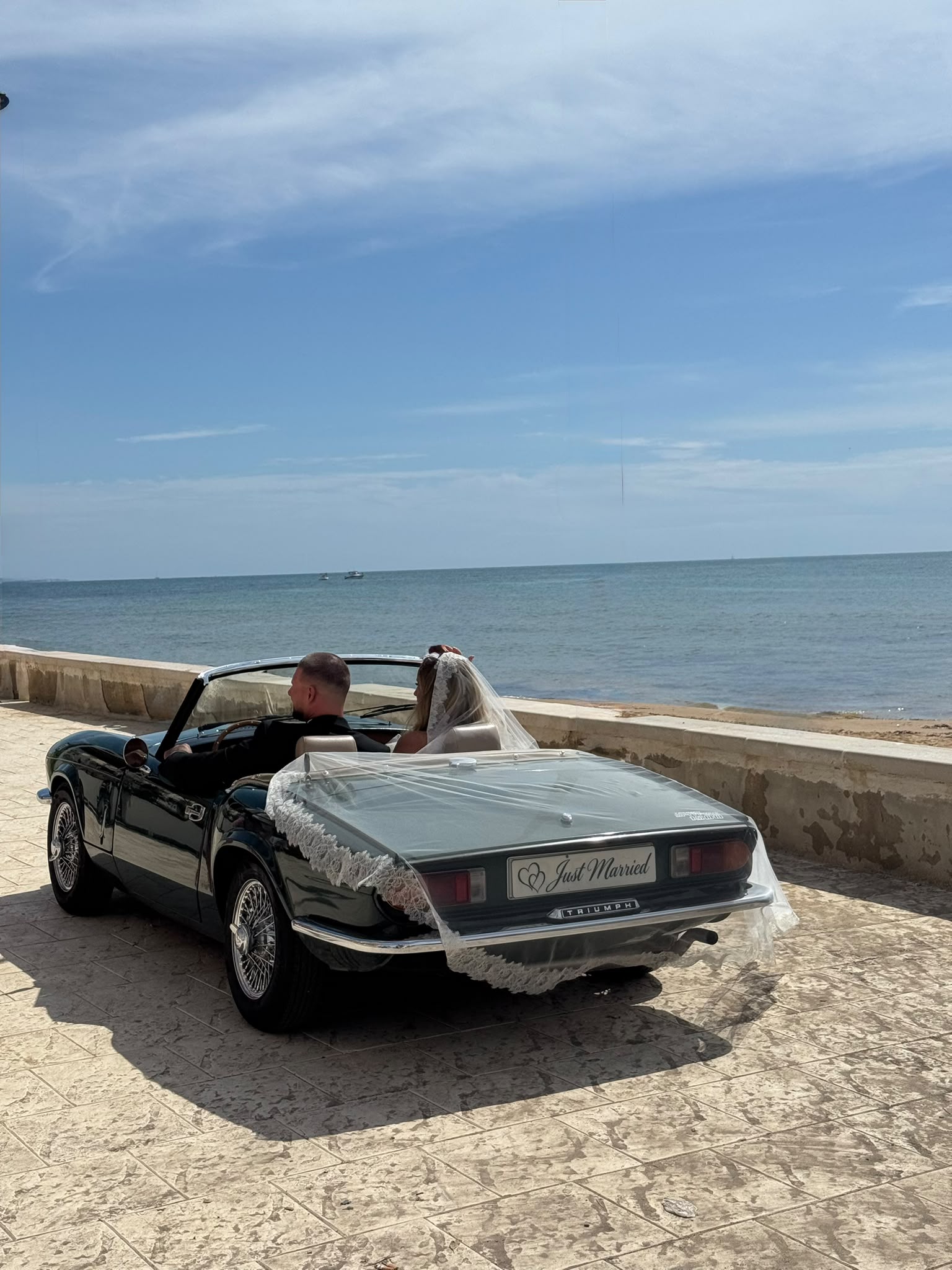 Gli sposi a bordo della Triumph davanti al mare